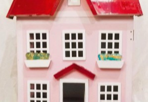 Casa de bonecas em tons rosa e grená.