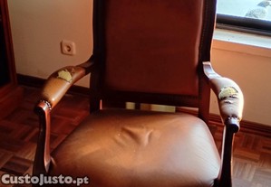 Poltrona clássica de madeira com estofos em pele castanha.